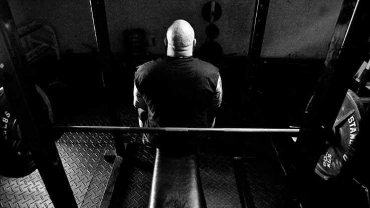 Homem sentado no banco do supino